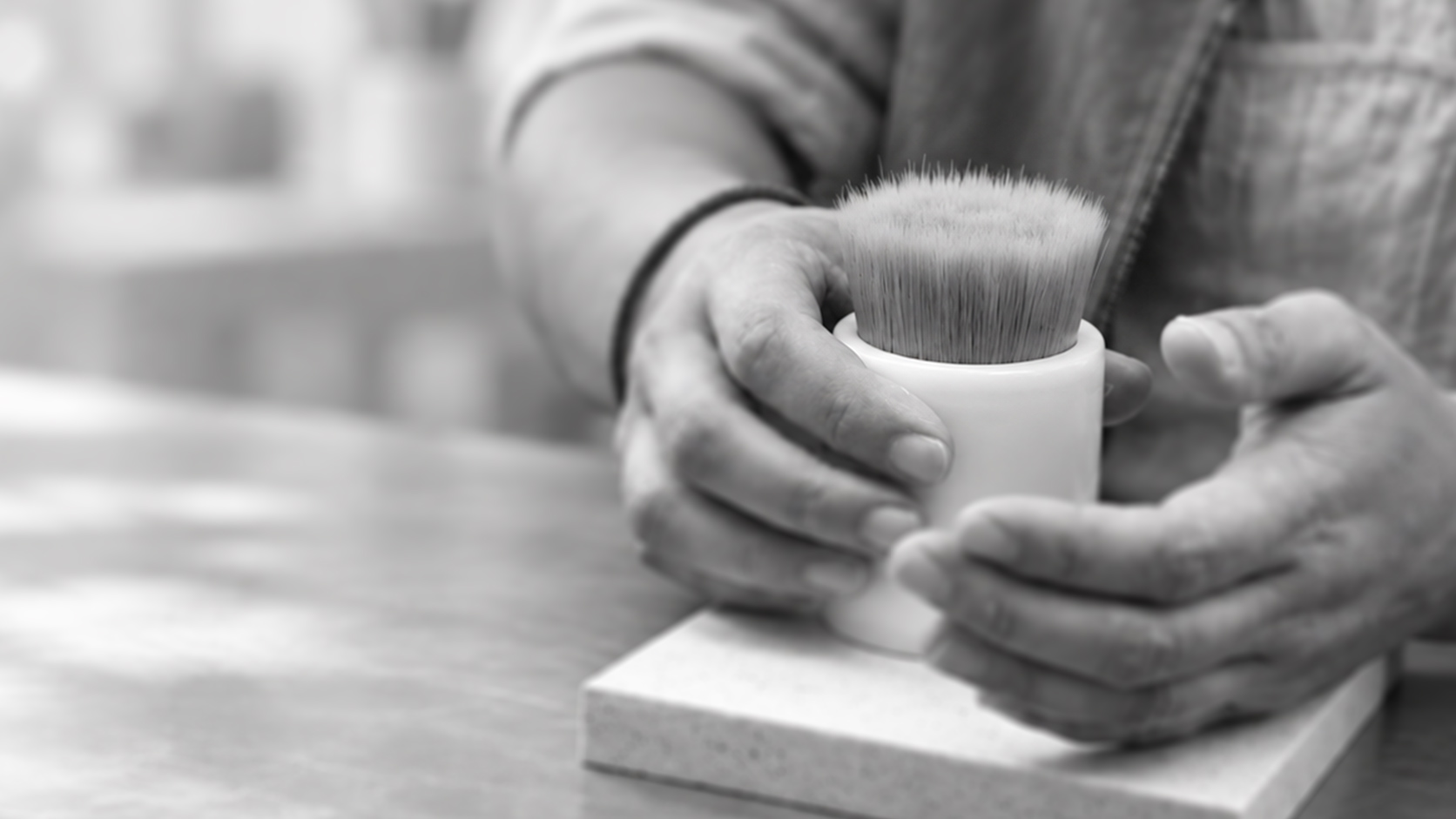 Hands assembling a dense makeup-brush head into a white cylindrical ferrule